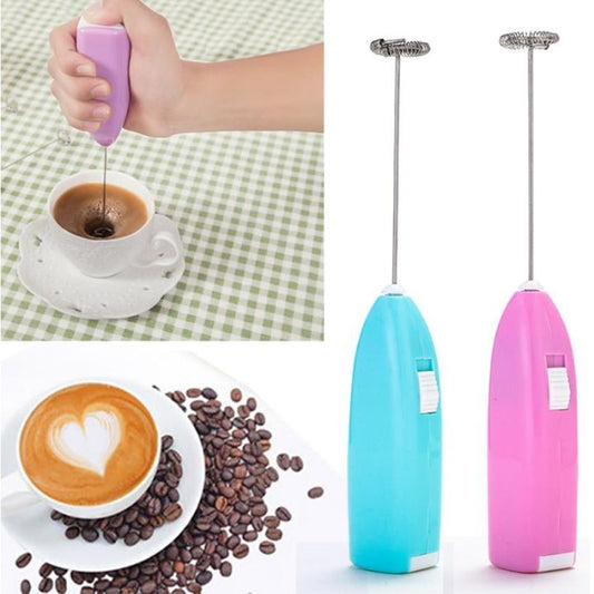 one handheld milk frothers, one blue and one pink, with a coffee cup and beans on a checkered tablecloth.