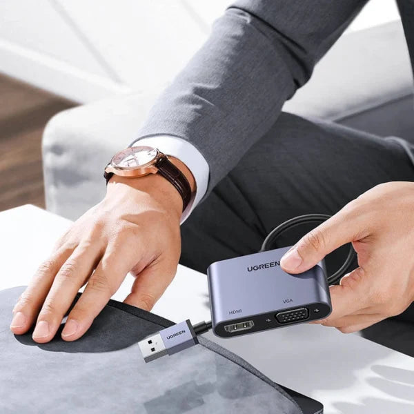Person holding a Ugreen USB hub with multiple ports on a desk.