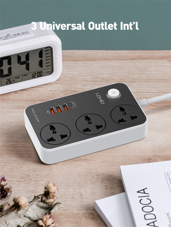 Power strip with multiple outlets on a wooden surface next to a digital clock and book.