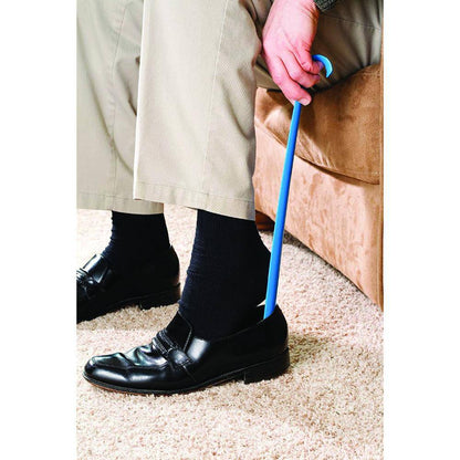 Person wearing black shoes and beige pants, holding a blue cane on a carpeted floor.